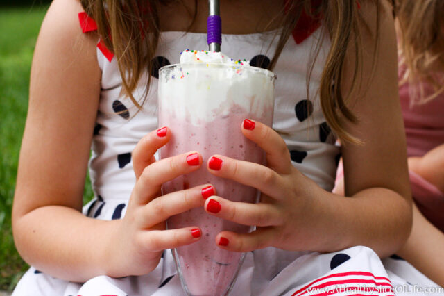 little girl holding milkshake
